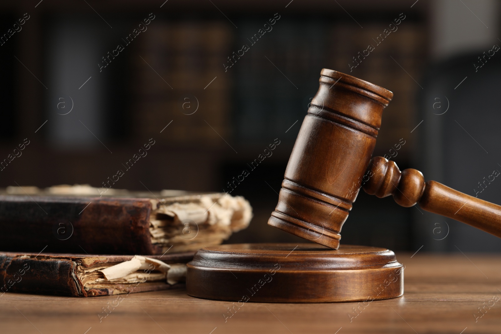 Photo of Wooden gavel and antique books on table, closeup