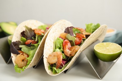 Delicious tacos with shrimps and lime on white table, closeup