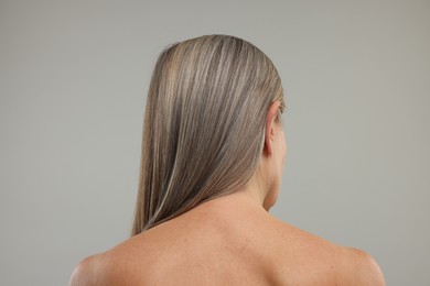 Mature woman with healthy skin on grey background, back view