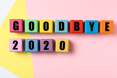 Cubes with phrase Goodbye 2020 on color background, flat lay