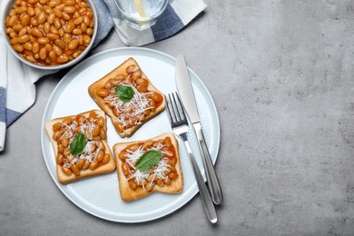 Photo of Toasts with delicious canned beans on light grey table, flat lay. Space for text