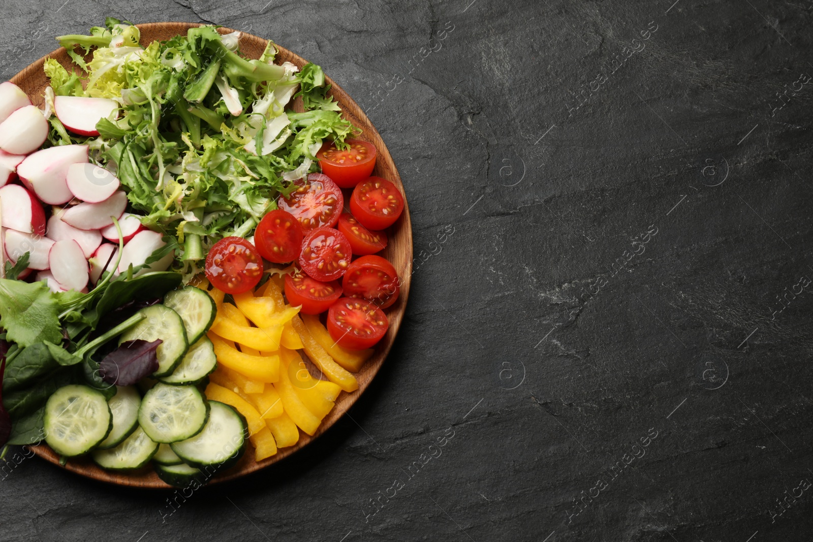 Photo of Vegetarian diet. Plate with tasty vegetables on black table, top view. Space for text