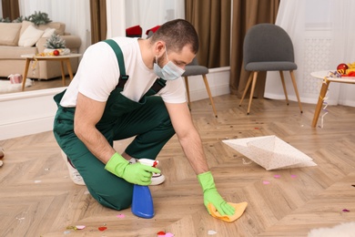 Photo of Man from cleaning service working in messy room after New Year party