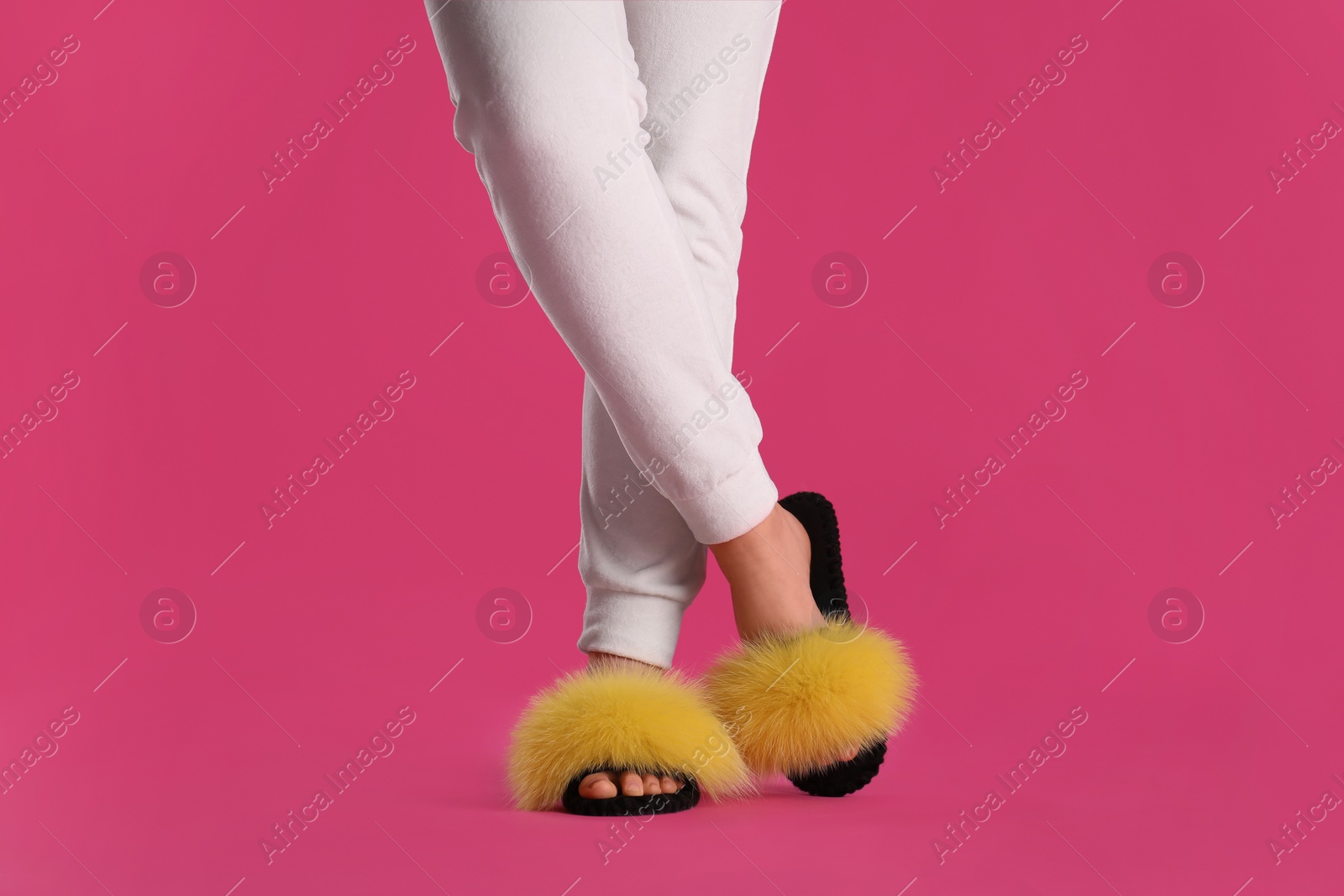 Photo of Woman in fluffy slippers on pink background, closeup