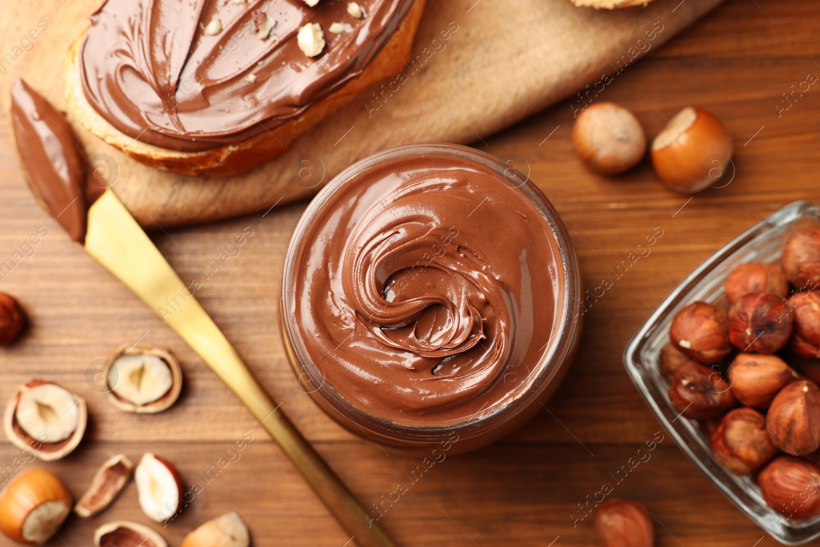 Photo of Flat lay composition with tasty chocolate hazelnut spread on wooden table