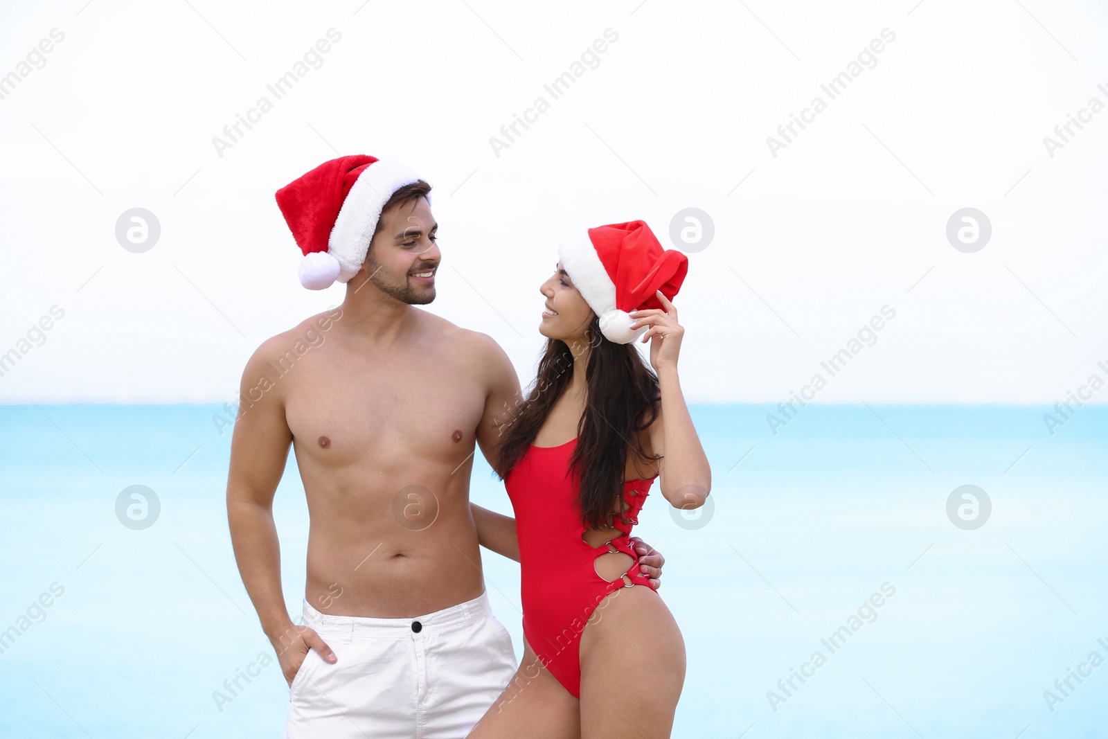 Photo of Happy young couple with Santa hats together on beach