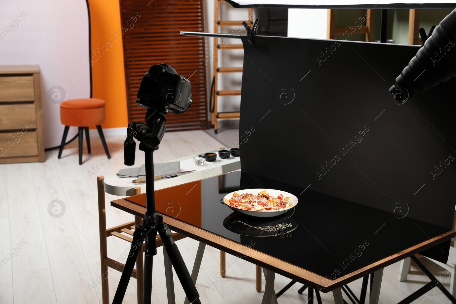 Photo of Professional equipment and salad with prosciutto on table in photo studio. Food photography