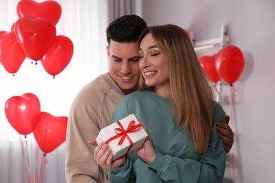 Lovely couple with gift in room. Valentine's day celebration