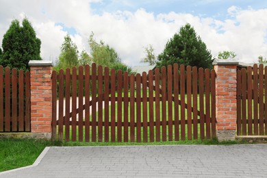 Wooden brown gates near beautiful trees and lawn outdoors