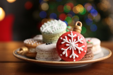 Beautifully decorated Christmas macarons on wooden table against blurred festive lights, closeup. Space for text