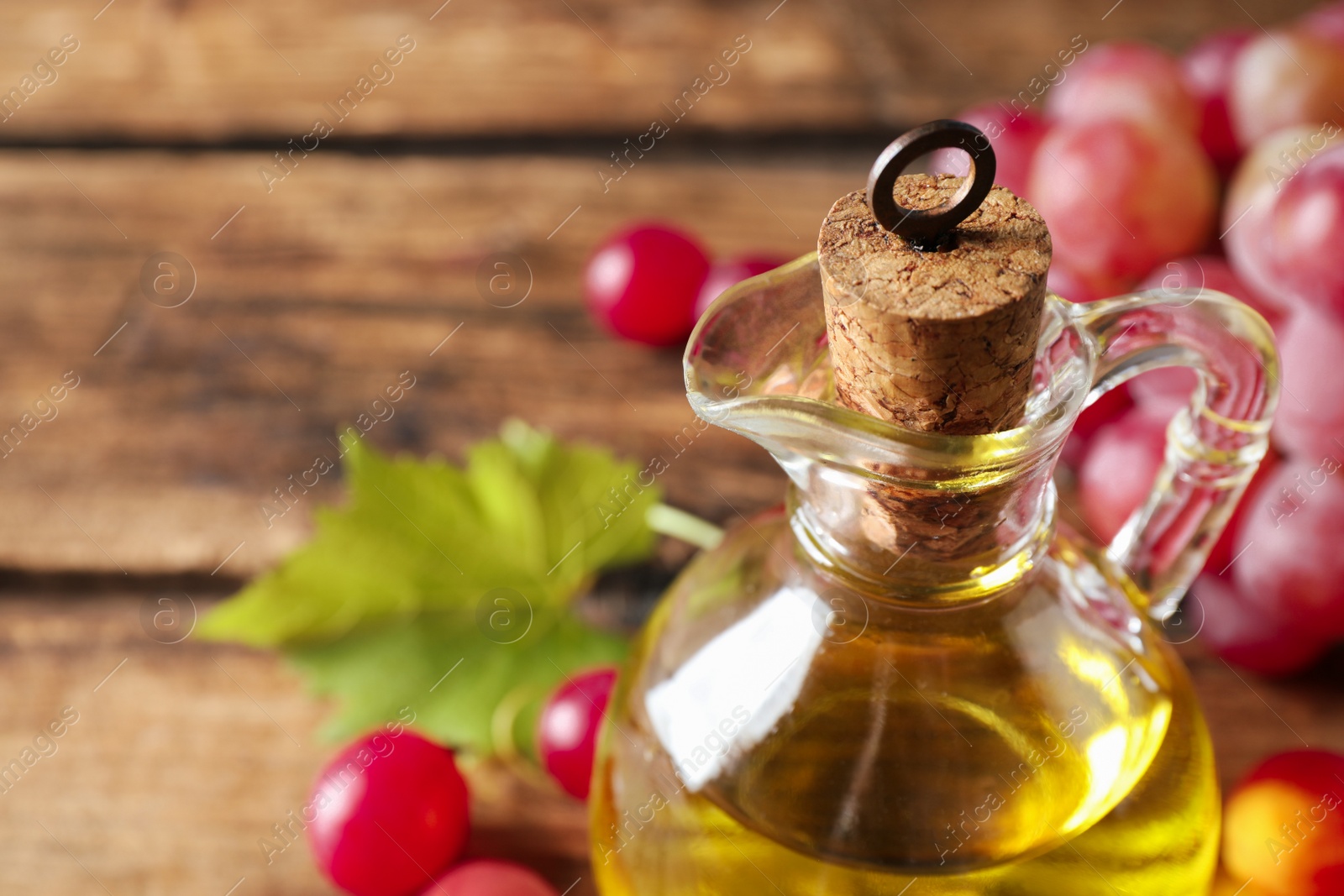 Photo of Jug of natural grape seed oil on table, closeup with space for text. Organic cosmetic