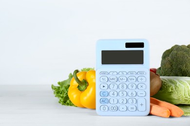 Calculator and food products on white wooden table, space for text. Weight loss concept