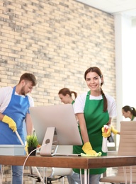 Team of professional janitors in uniform cleaning office