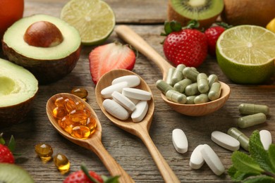 Photo of Different vitamin pills and fresh fruits on old wooden table