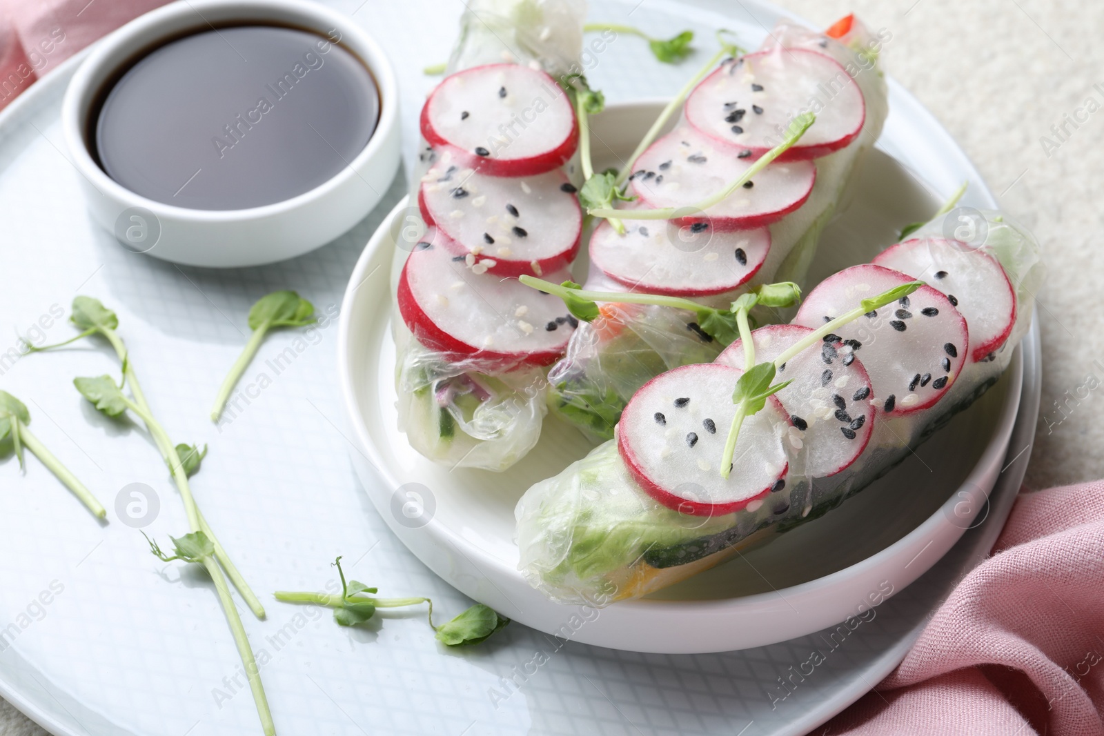 Photo of Delicious spring rolls, microgreens and soy sauce on table, closeup