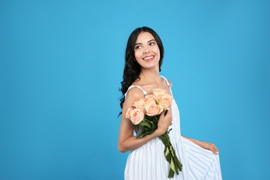 Portrait of smiling woman with beautiful bouquet on light blue background. Space for text