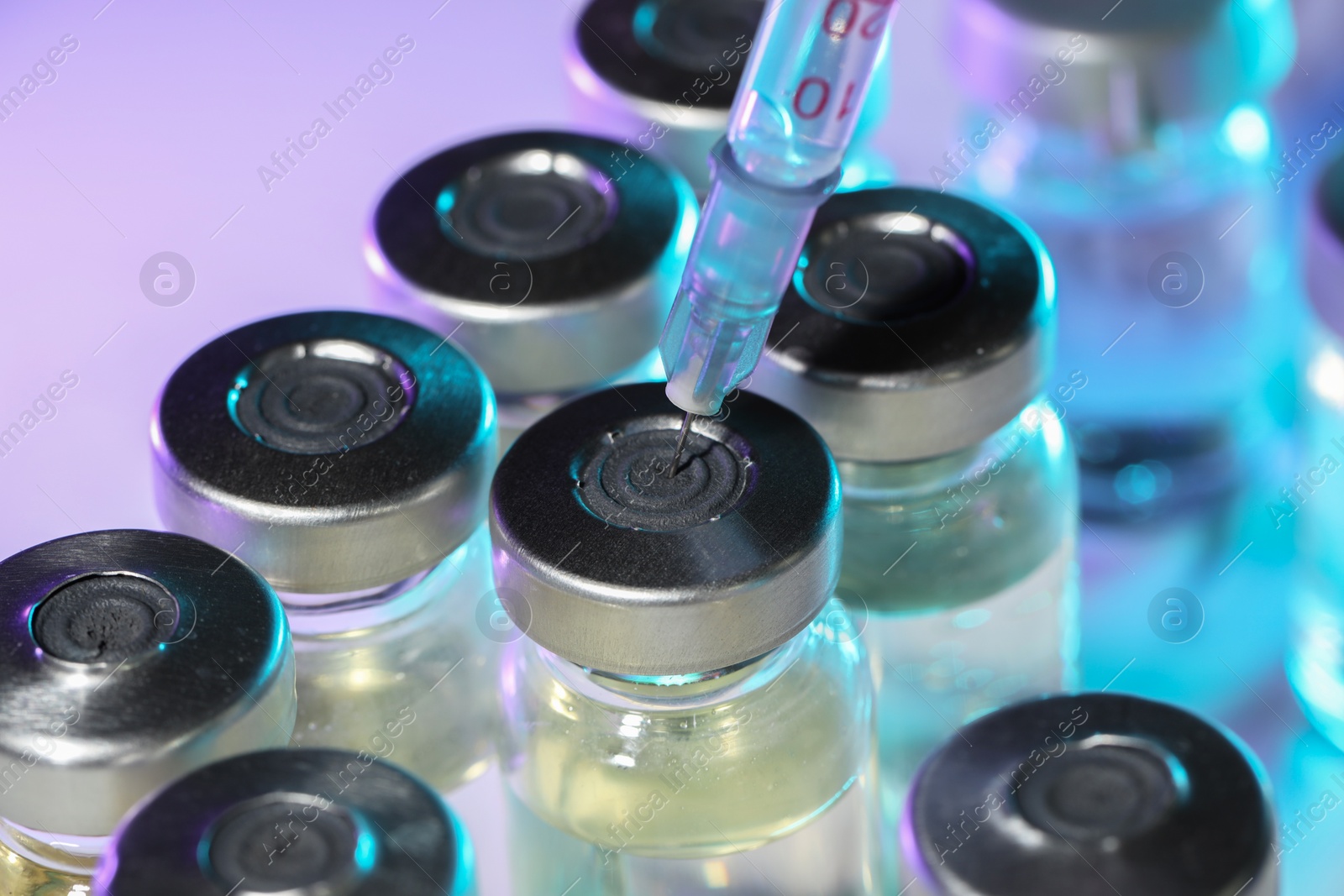 Photo of Filling syringe with medicine from vial on color background, closeup