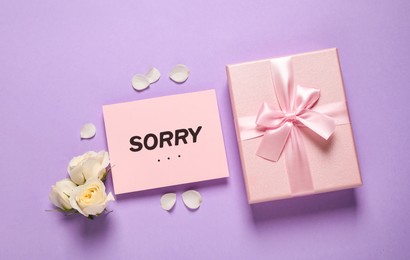 Apology. Pink card with word Sorry, gift box and beautiful roses on violet background, flat lay