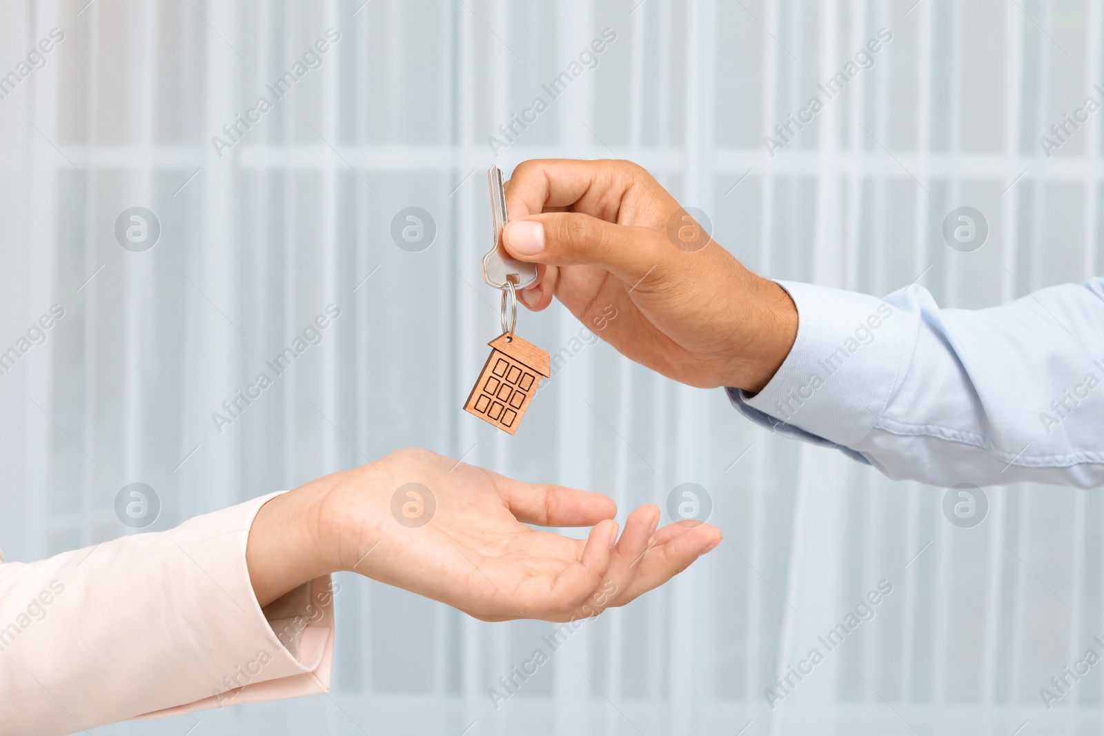 Photo of Real estate agent giving key to woman on blurred background
