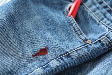 Pen and stain of red ink on jeans, closeup