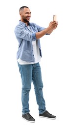 Smiling young man taking selfie with smartphone on white background