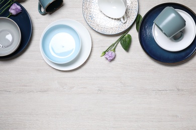 Photo of Flat lay composition with beautiful dishware and flowers on white wooden table. Space for text
