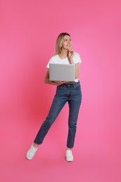 Photo of Young woman with modern laptop on pink background