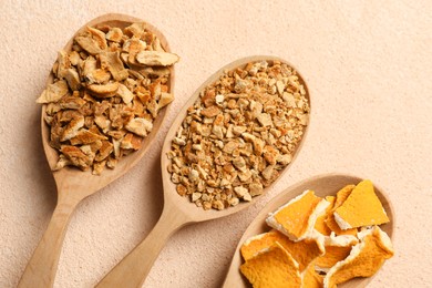 Photo of Spoons with dried orange seasoning zest and peel on beige textured table, flat lay