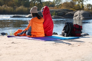Photo of Campers sitting in sleeping bags on wild beach