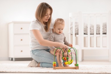 Photo of Children toys. Mother and her little son playing with bead maze on rug at home