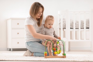 Children toys. Mother and her little son playing with bead maze on rug at home