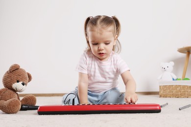 Cute little girl playing with toy piano at home