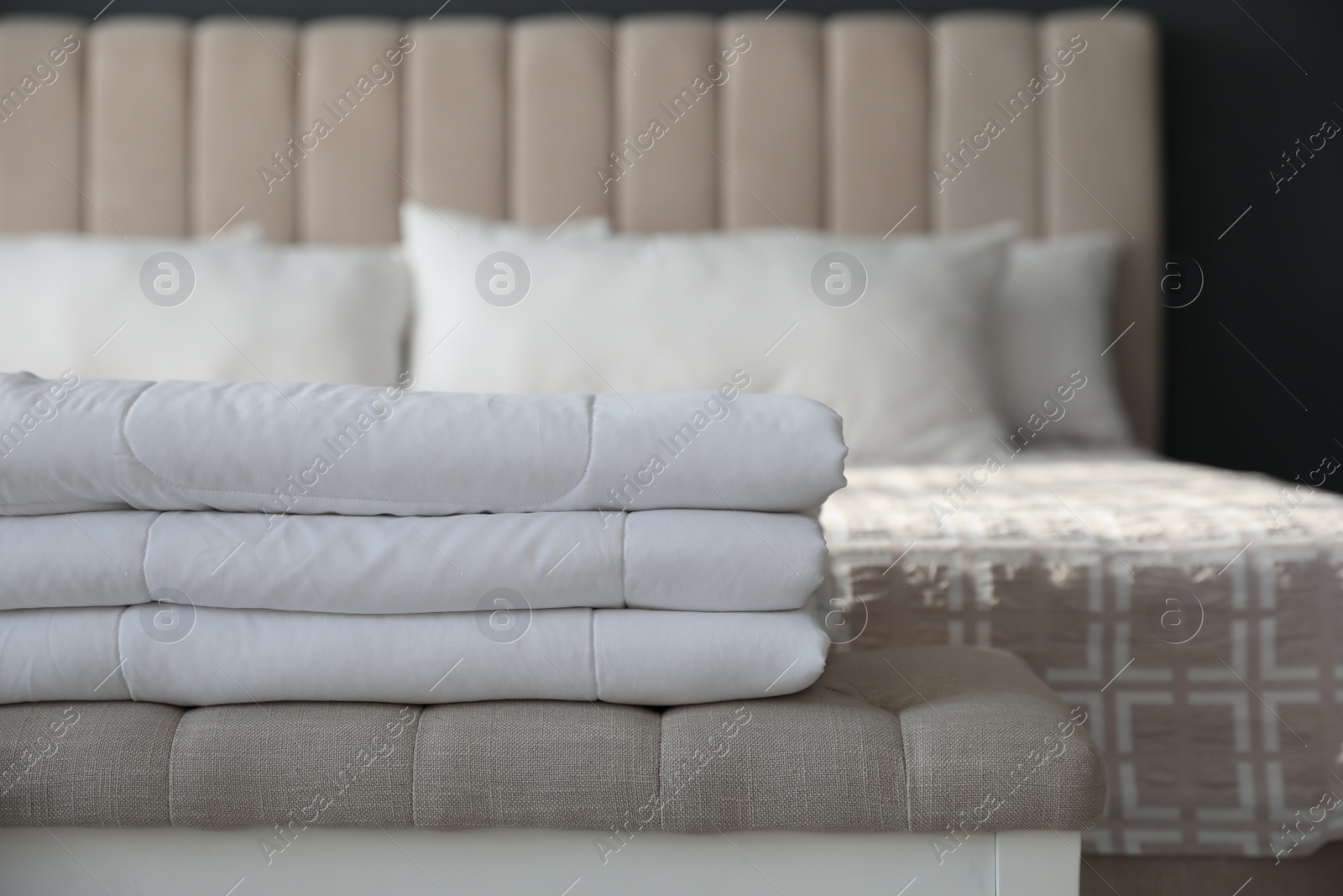 Photo of Folded clean blanket on bed bench in room, closeup