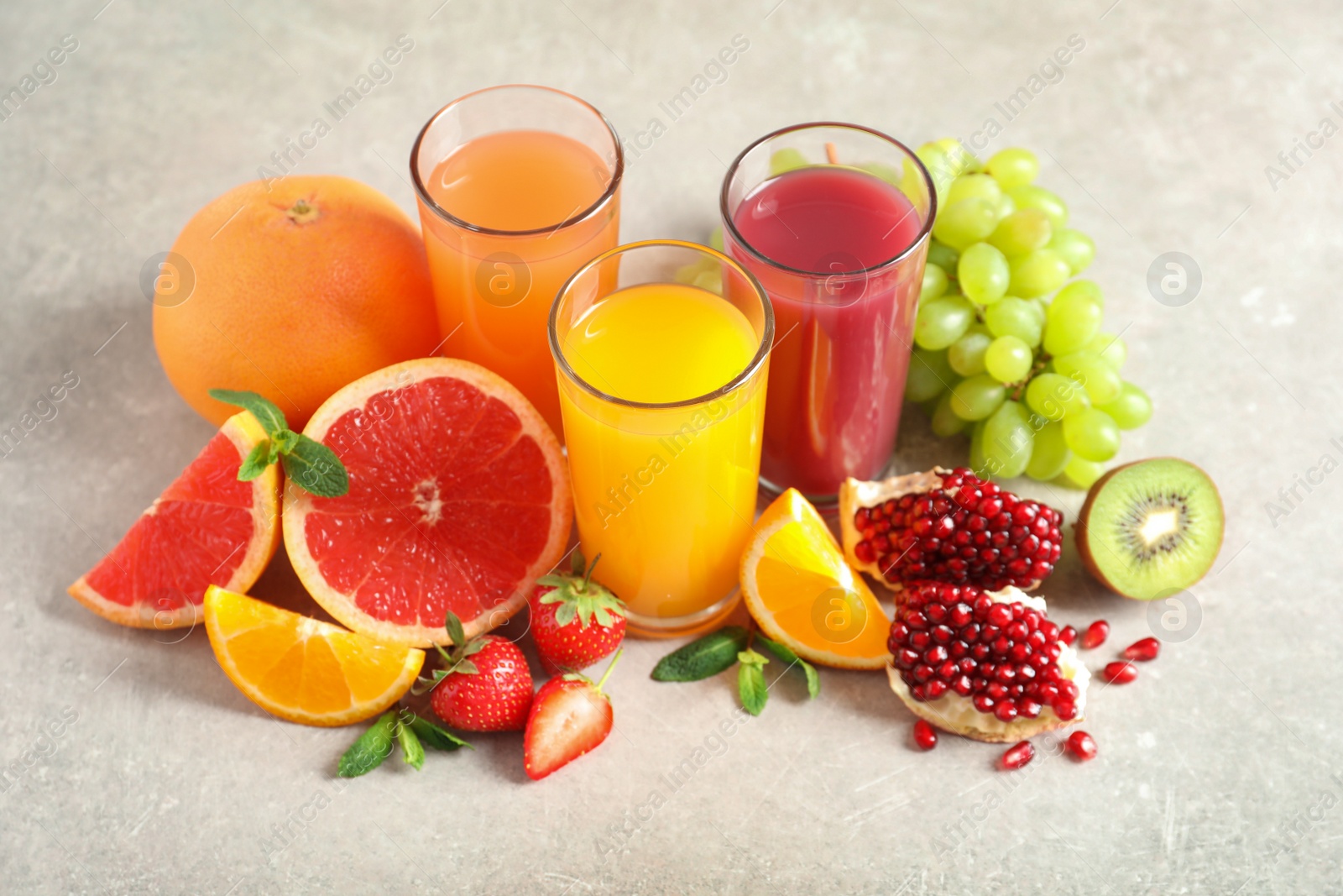 Photo of Glasses of different juices and fresh fruits on table