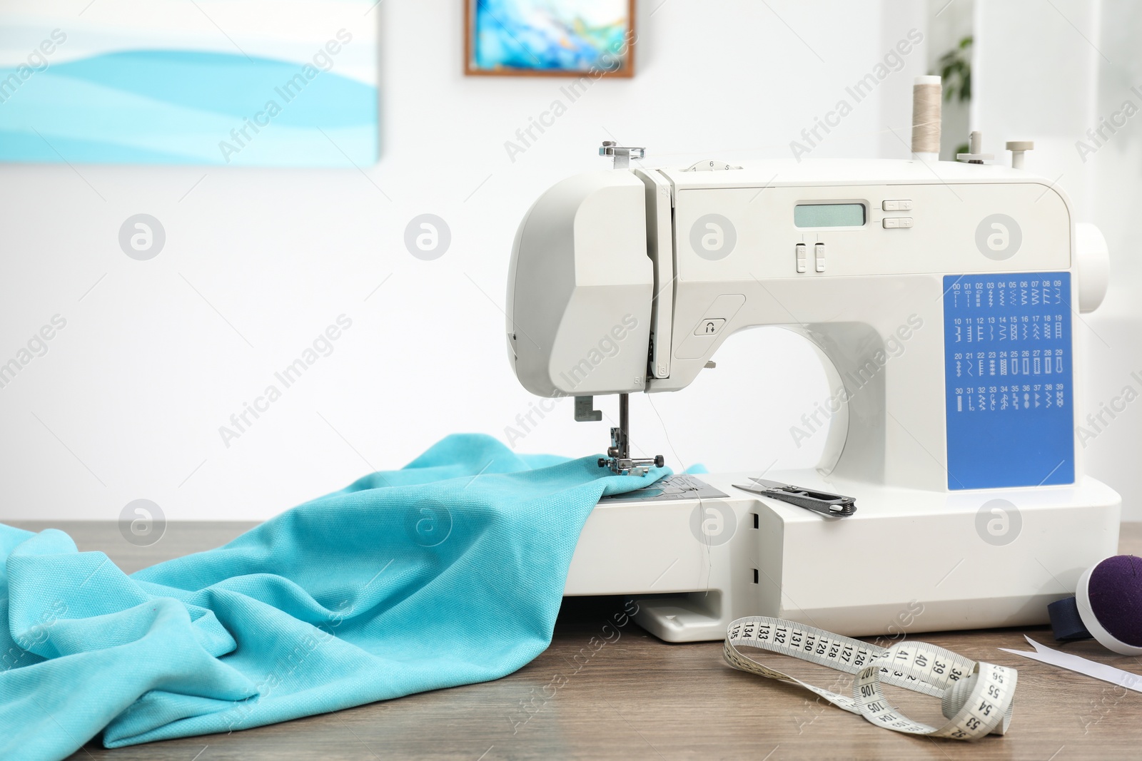 Photo of White sewing machine and cloth on wooden table indoors