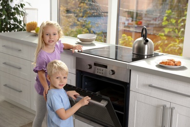 Little kids baking cookies in oven at home