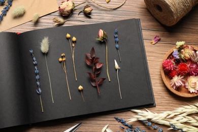 Photo of Flat lay composition with beautiful dry flowers and herbarium album on wooden table