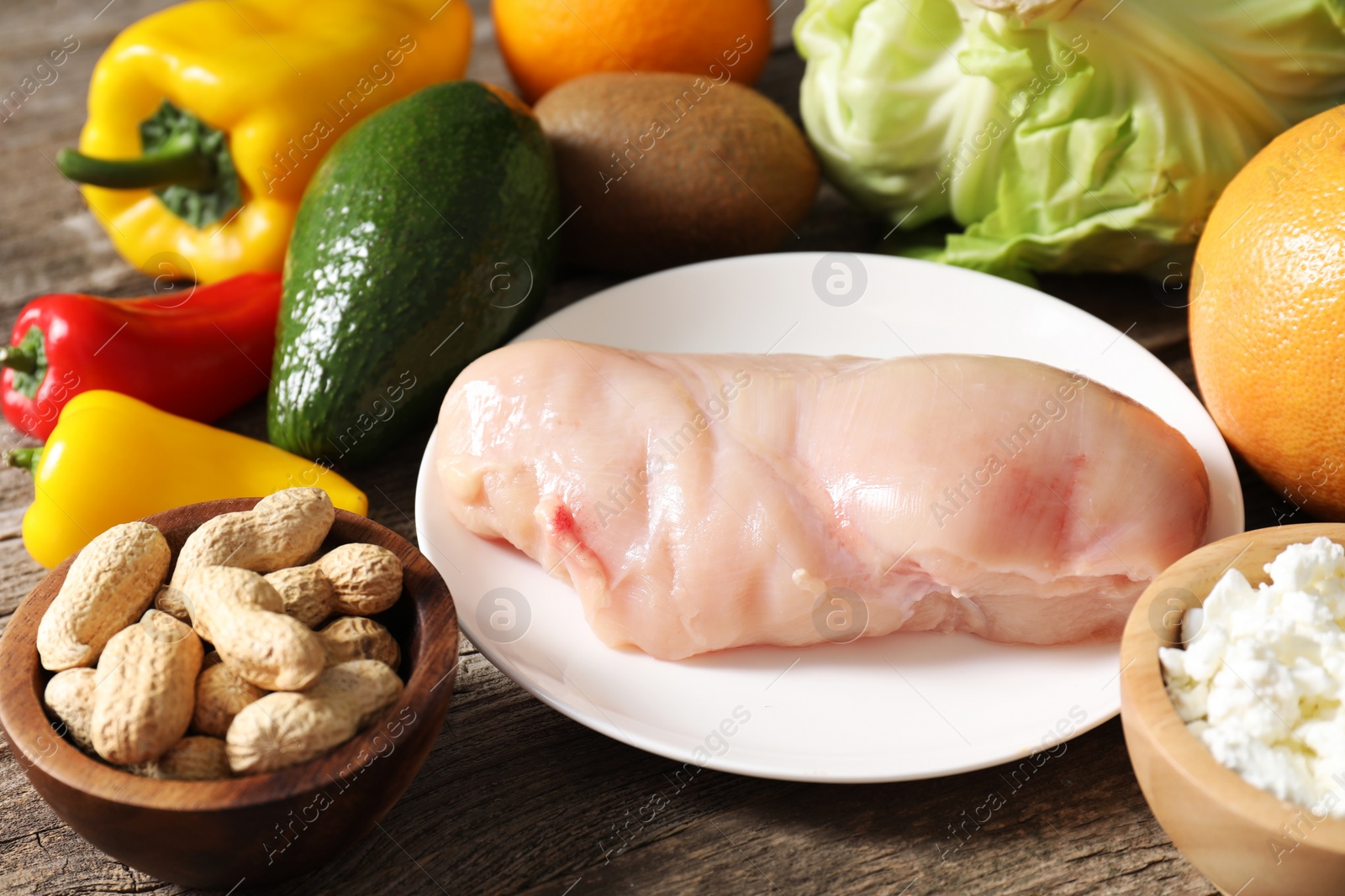 Photo of Healthy meal. Different vegetables and raw chicken breast on wooden table, closeup