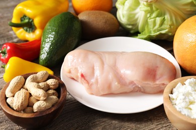 Healthy meal. Different vegetables and raw chicken breast on wooden table, closeup