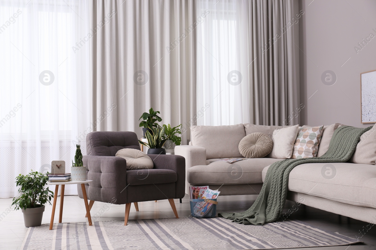 Photo of Comfortable armchair and sofa near window in living room. Interior design