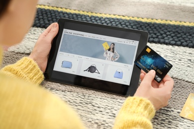 Woman with credit cards using tablet for online shopping on carpet, closeup