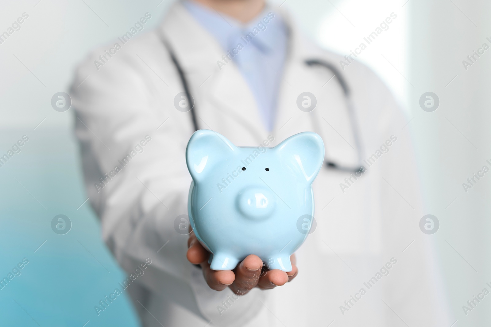 Photo of Doctor with piggy bank in hospital, closeup