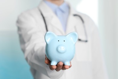 Photo of Doctor with piggy bank in hospital, closeup