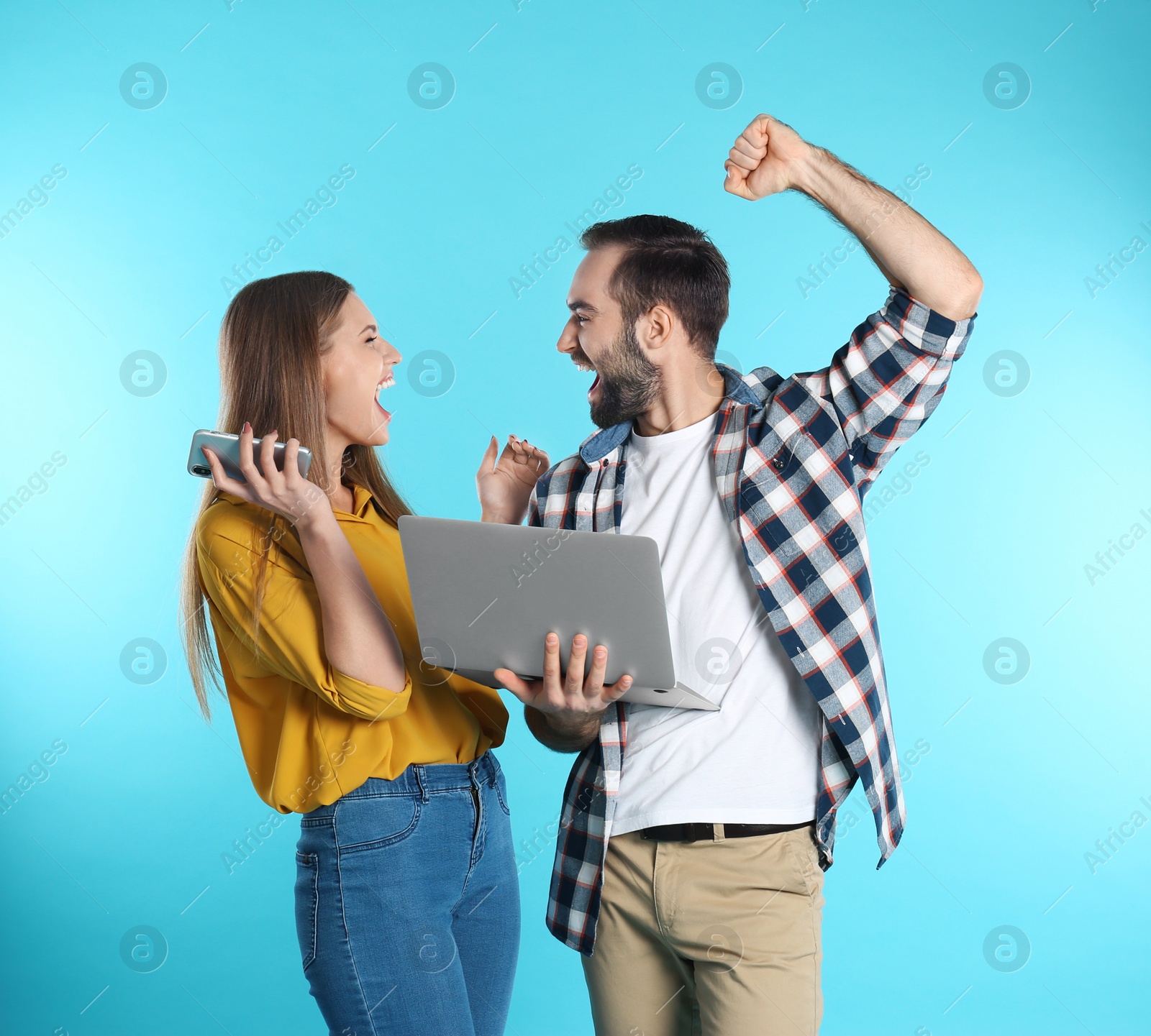 Photo of Emotional young people with laptop celebrating victory on color background