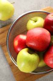 Fresh ripe apples in colander on light grey table, top view