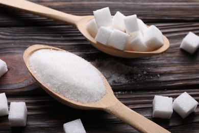 Photo of Spoons with different types of white sugar on wooden table, closeup