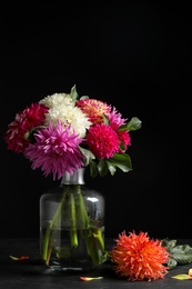 Beautiful dahlia flowers in vase on table against black background