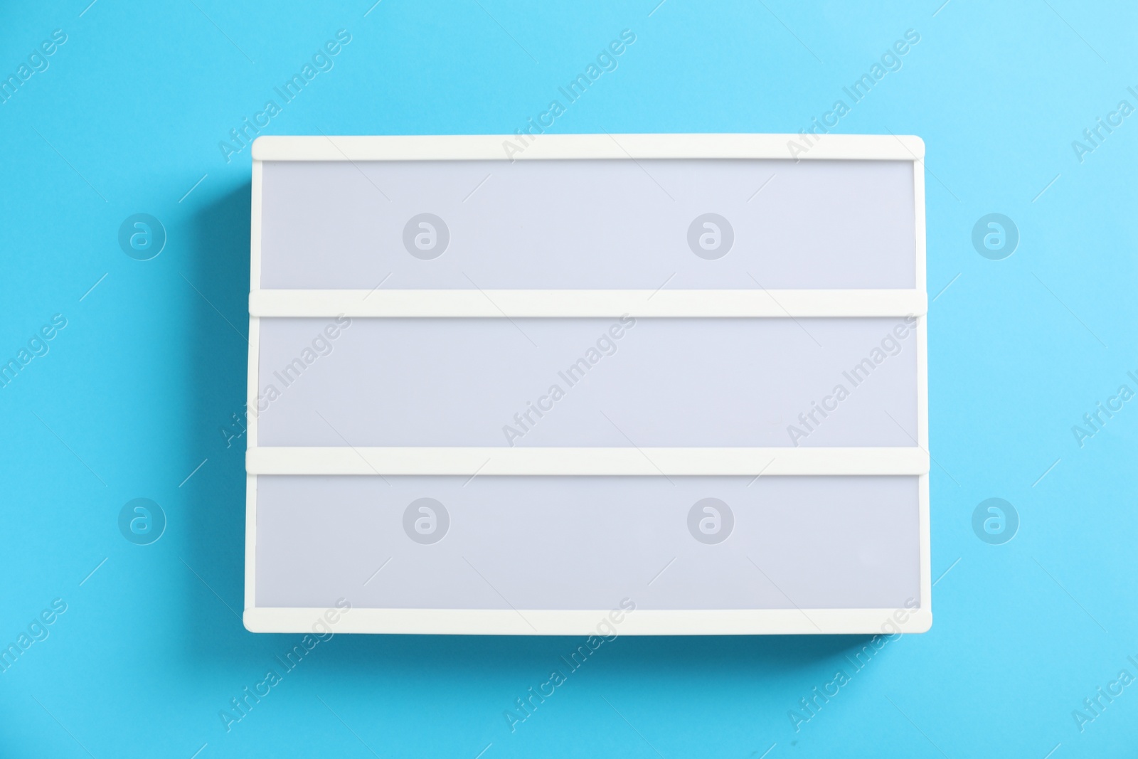 Photo of Blank letter board on light blue background, top view