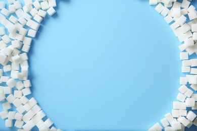 Frame of refined sugar cubes on color background, top view