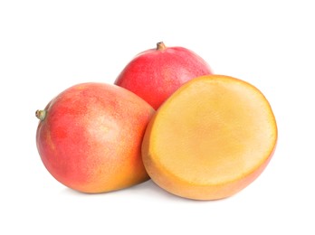 Delicious whole and cut mangoes on white background